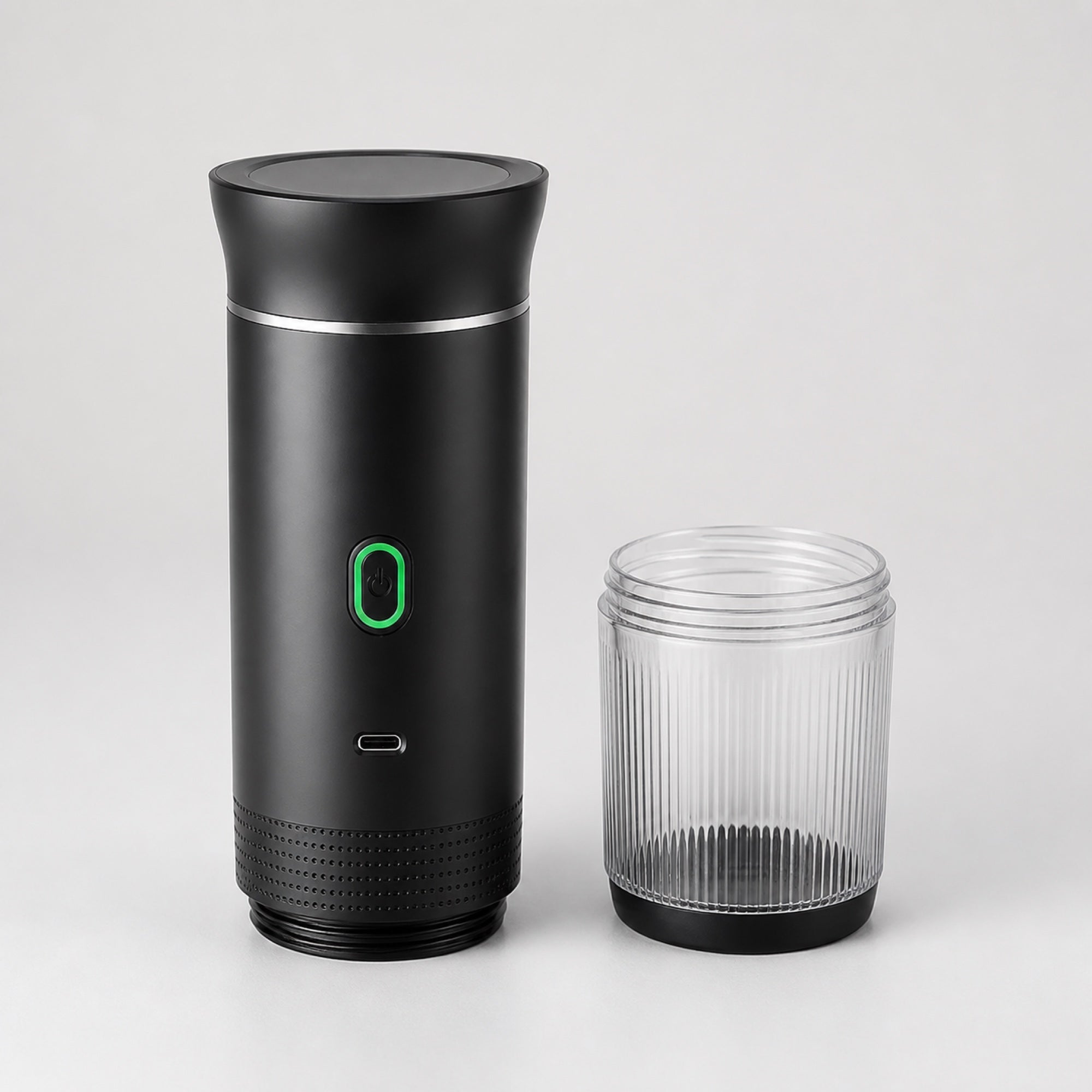 Tazzi portable espresso maker with the ribbed clear cup unscrewed and standing beside the black body, showing the thread