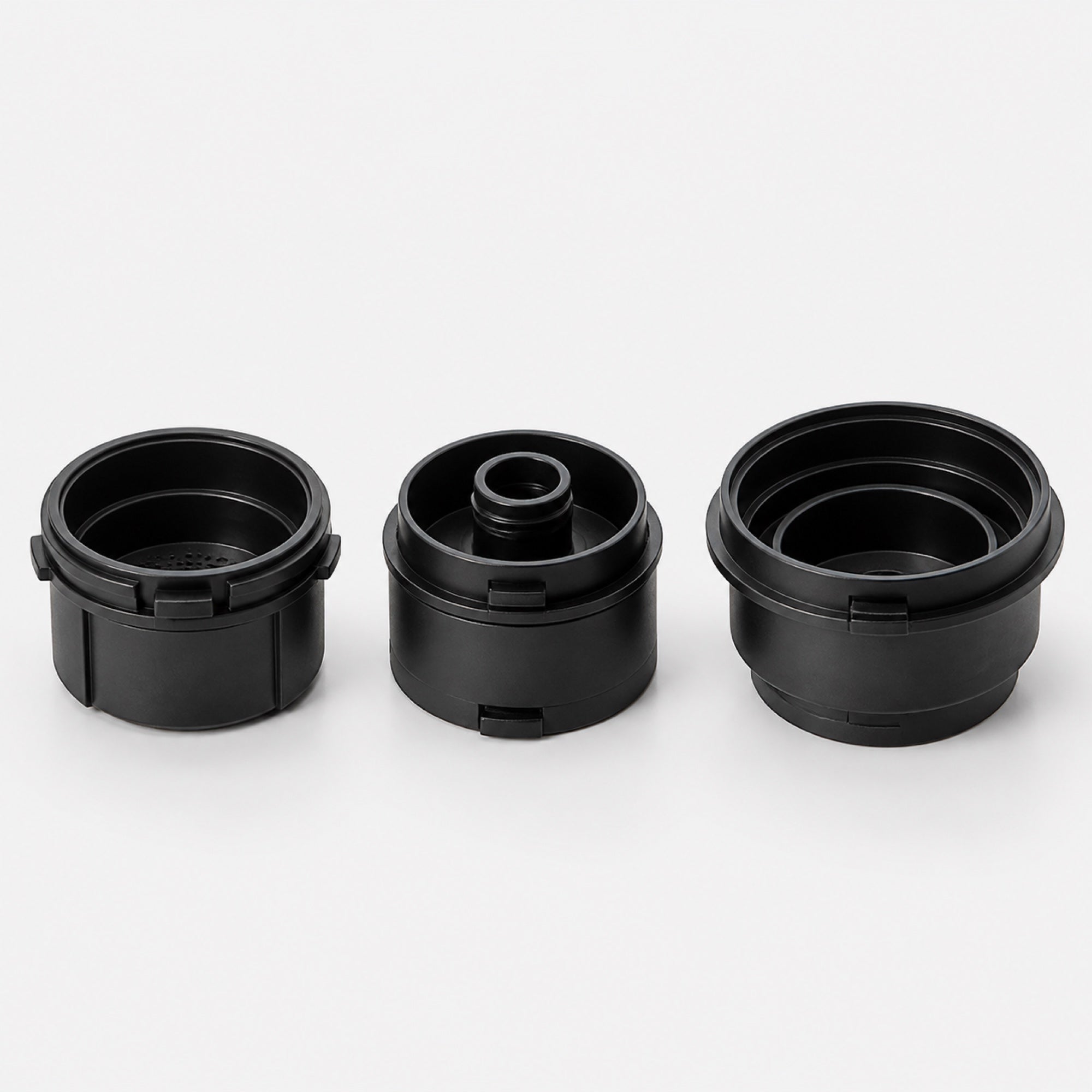 The three black Tazzi adapters side by side: ground coffee, Nespresso Original capsule base and Dolce Gusto capsule adapter